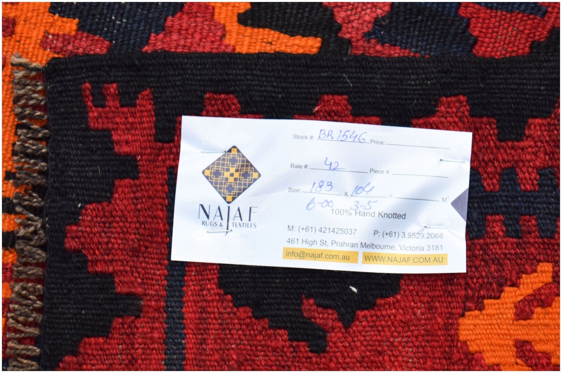 A handmade Afghan Maimana kilim featuring a geometric pattern in red, orange, and black wool.