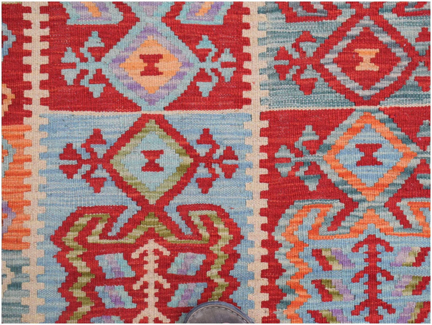 Handwoven Afghan Maimana kilim featuring a vibrant geometric pattern in red, blue, and orange.