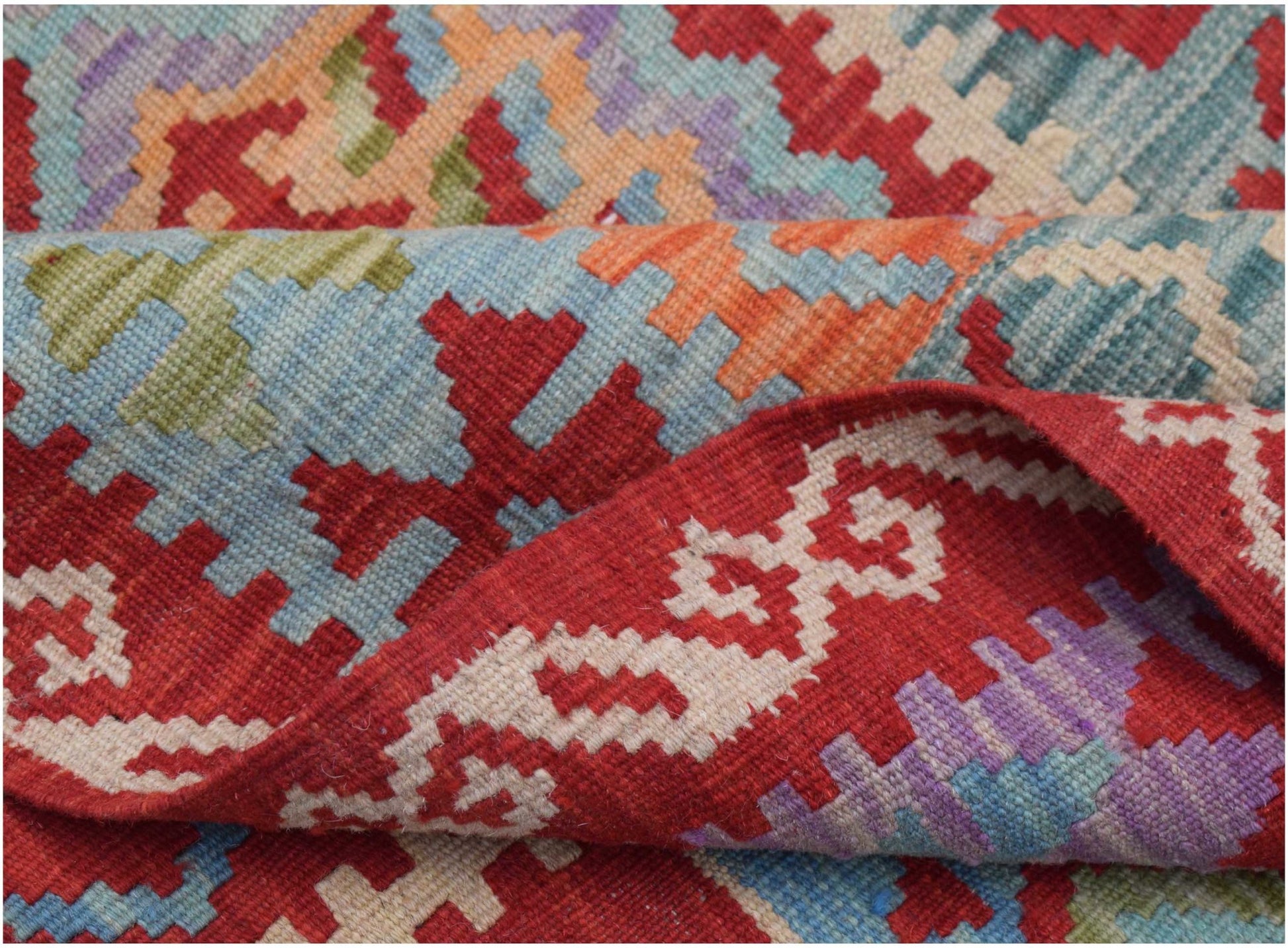 A handwoven Afghan Maimana kilim rug featuring a geometric pattern in red, blue, and orange wool.