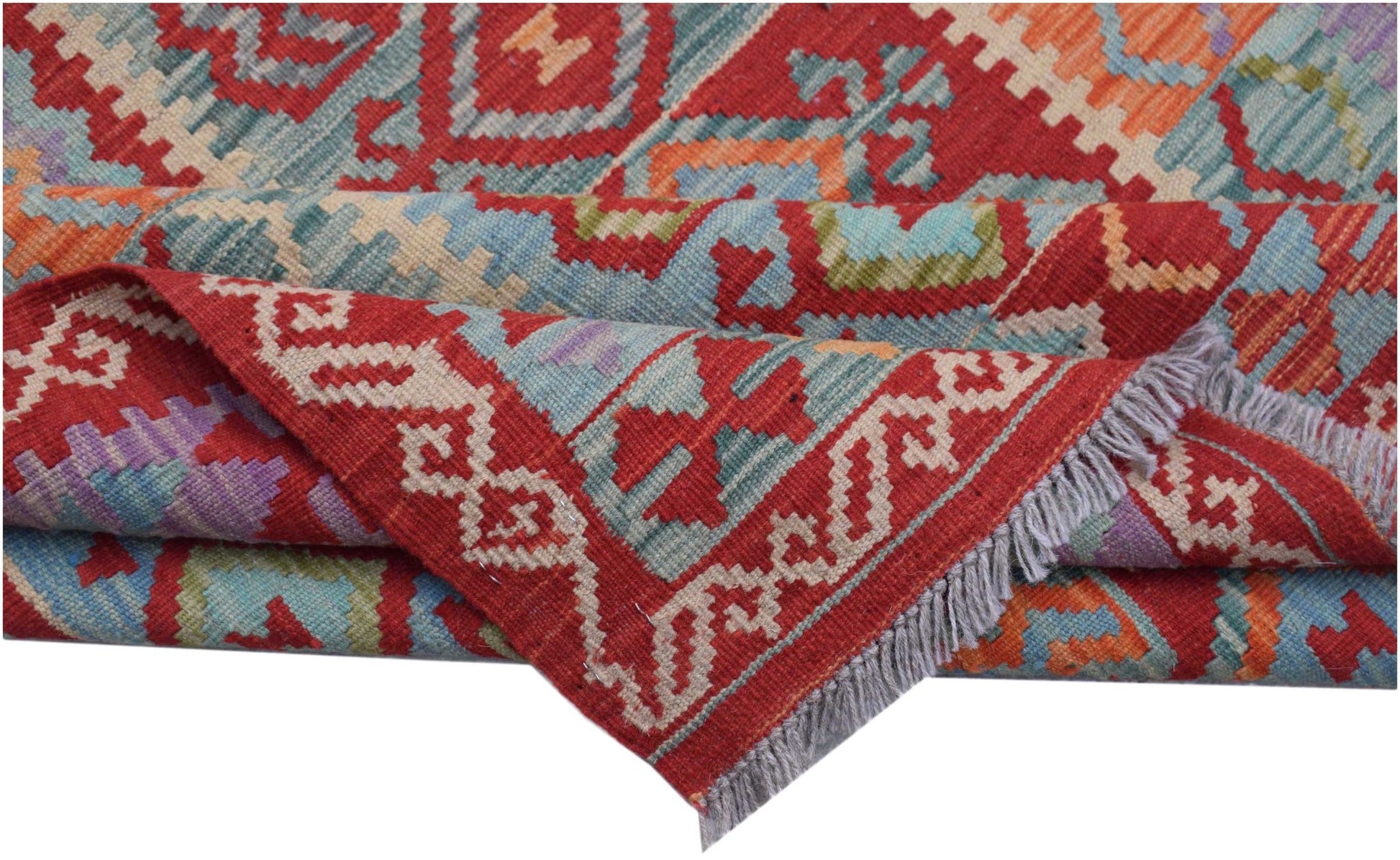 A folded Afghan Maimana kilim rug featuring geometric patterns in red, blue, and orange wool.