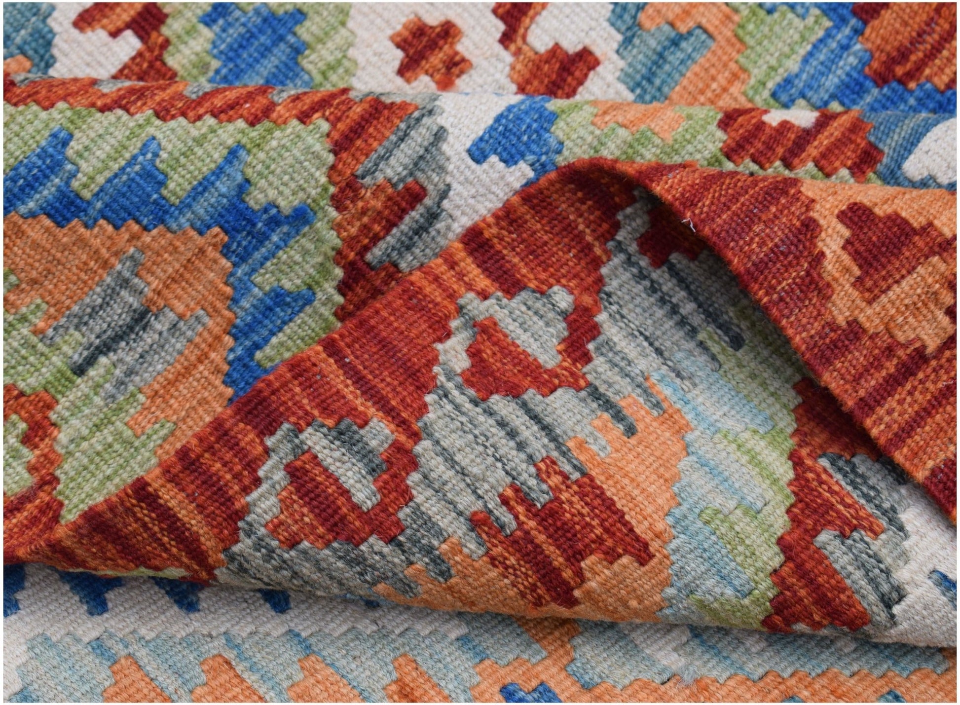 A handwoven Afghan Maimana kilim rug featuring a geometric pattern in vibrant wool colors.