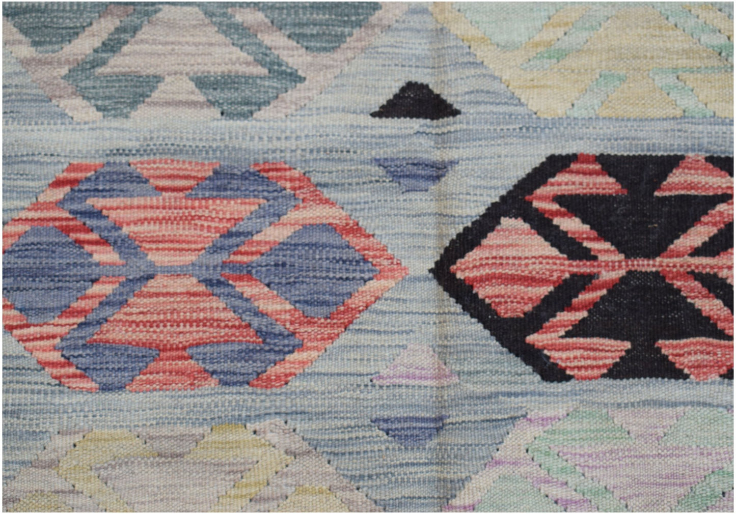 A handwoven Afghan Maimana kilim featuring a geometric pattern in red, blue, and neutral tones.