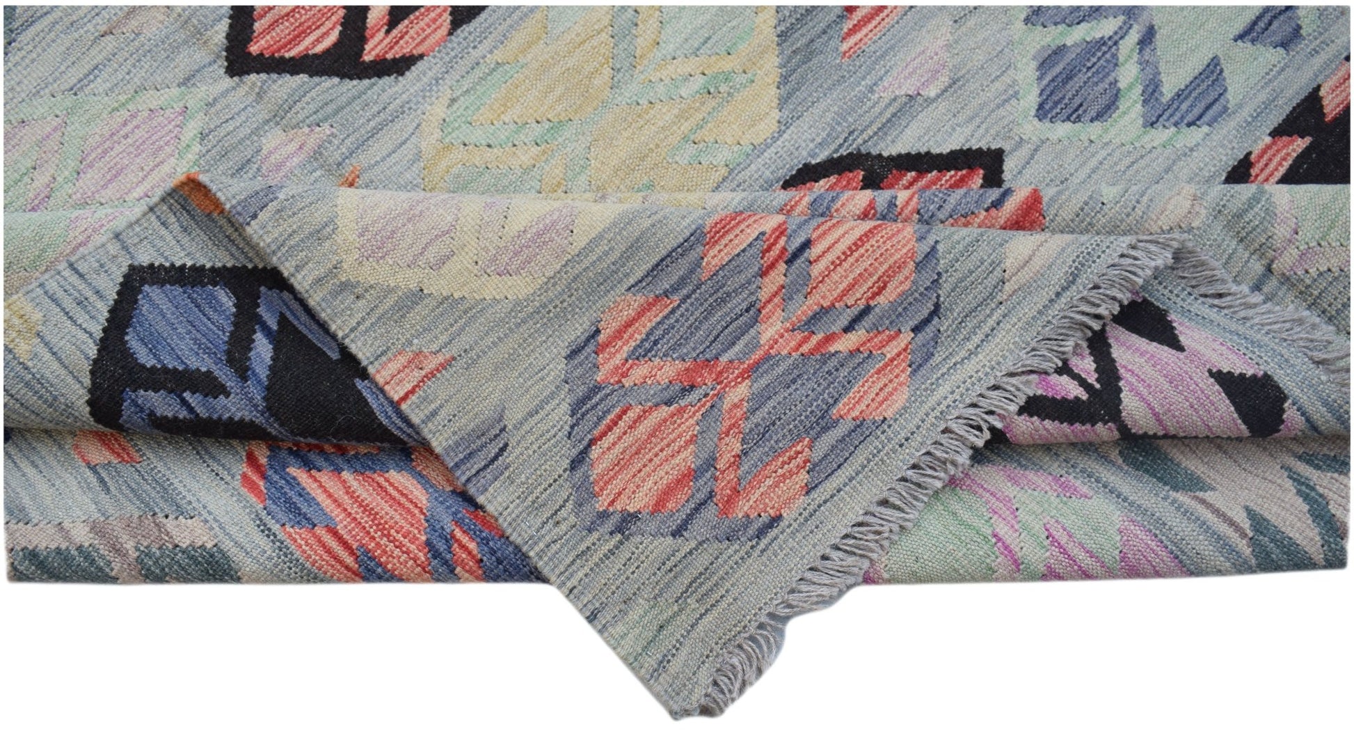 A handwoven Afghan Maimana kilim rug featuring a geometric pattern in muted, multicolored tones.