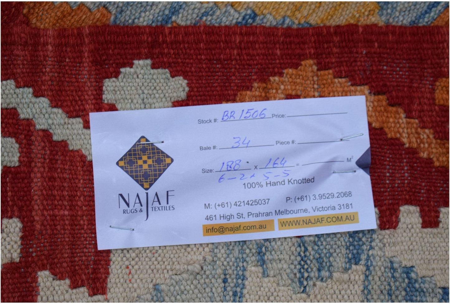 An Afghan Maimana Kilim rug featuring a geometric pattern in red, orange, blue, and cream.