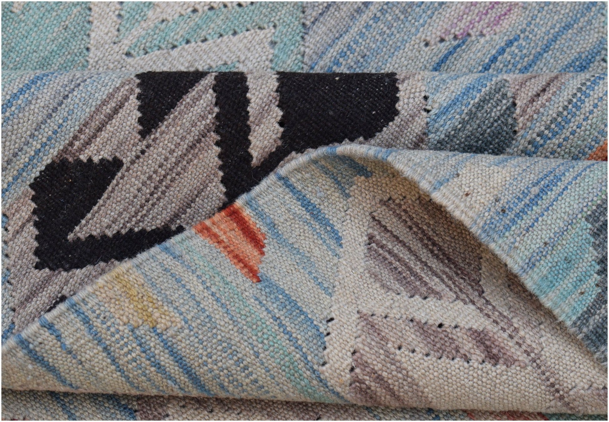 A close-up view of a handwoven Afghan Maimana kilim featuring a geometric pattern in wool.