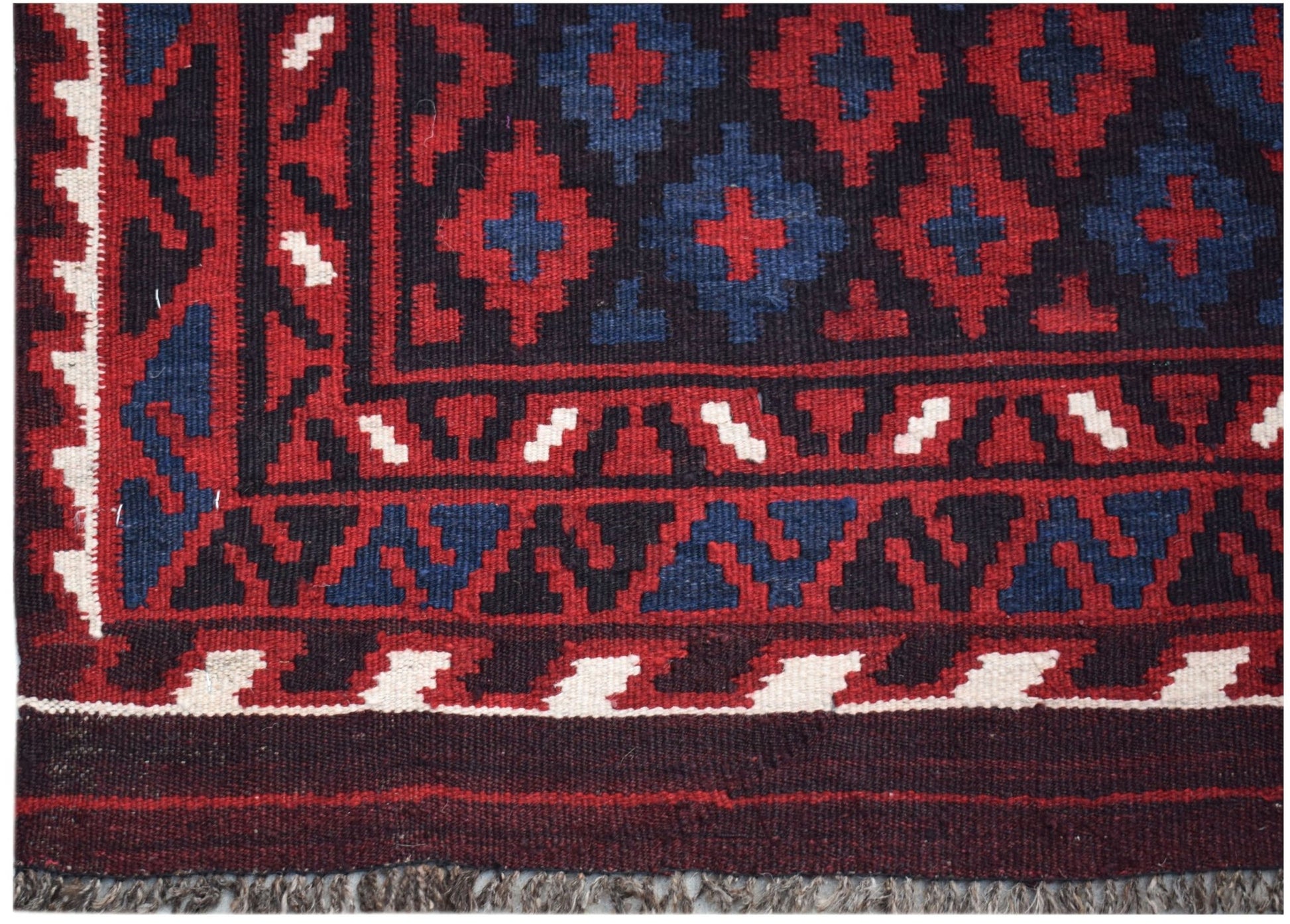 Handwoven Afghan Maimana kilim featuring a geometric pattern in red, blue, and cream wool.