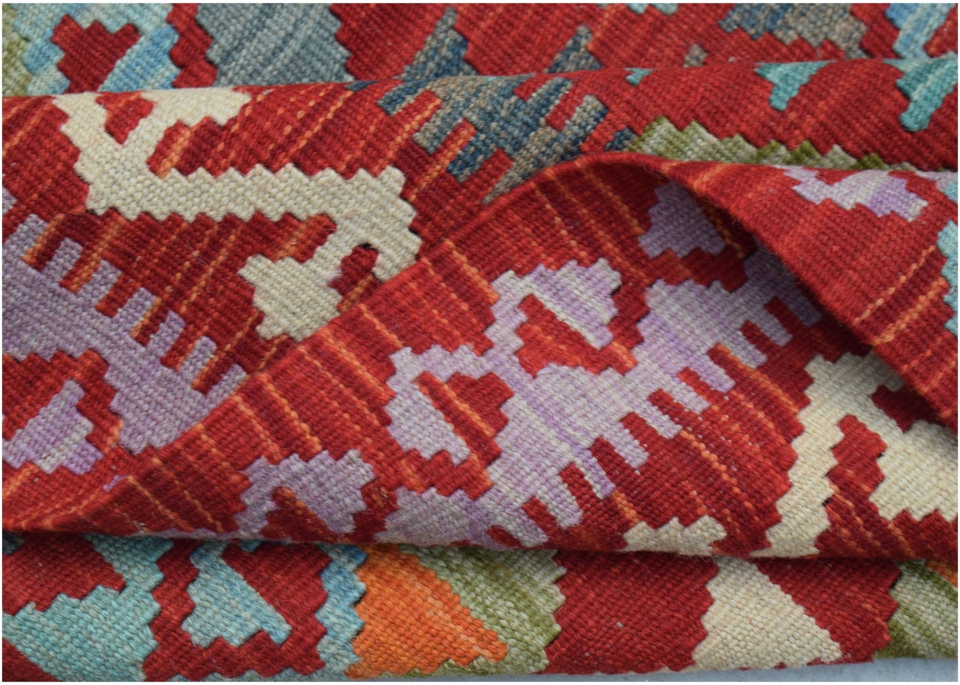 A handwoven Afghan Maimana kilim rug featuring a vibrant geometric pattern in wool.
