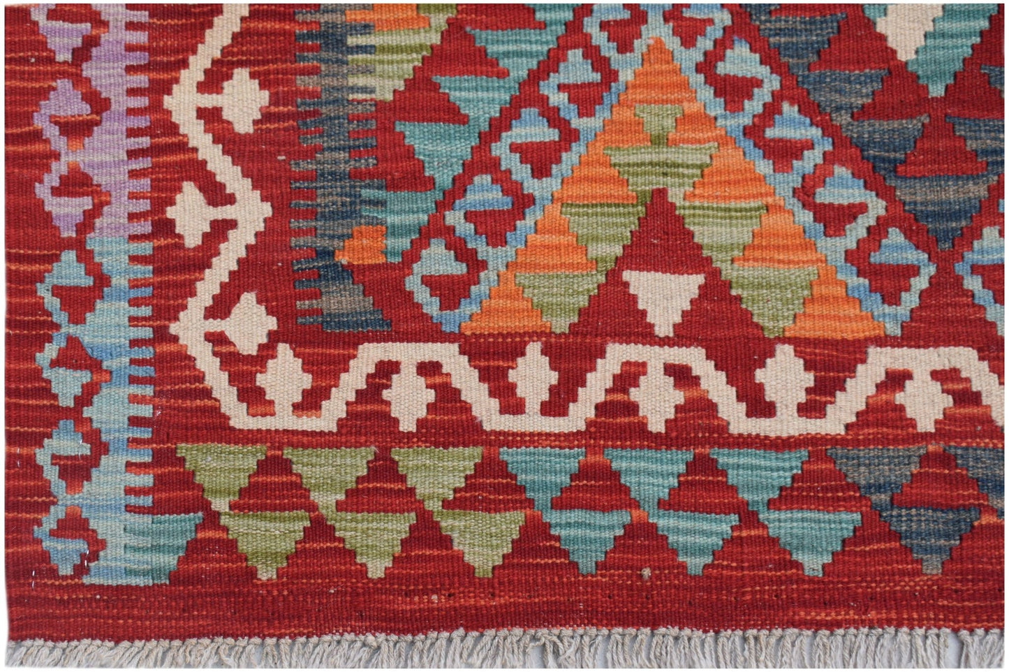 Handwoven Afghan Maimana kilim featuring a geometric pattern in red, blue, green, and orange.