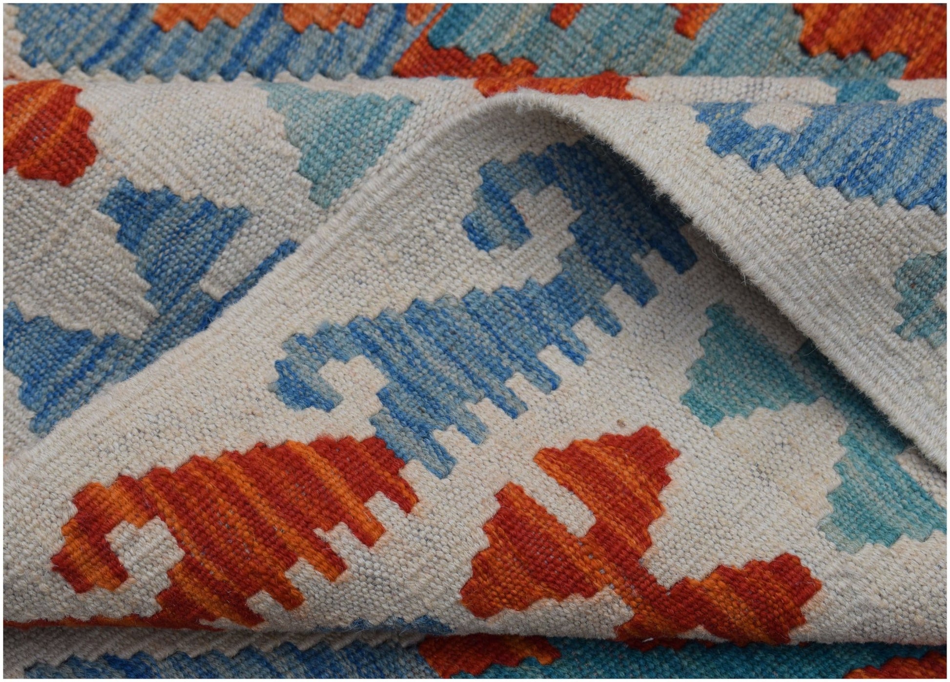 A handmade Afghan Maimana kilim rug featuring a geometric pattern in orange and blue on a cream base.