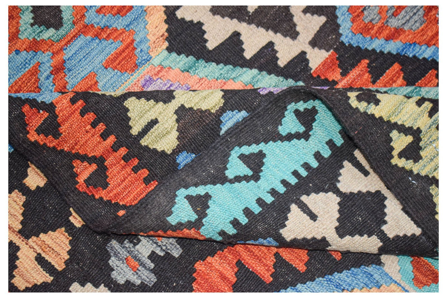 A handmade Afghan Maimana kilim featuring a geometric pattern in vibrant wool colors.