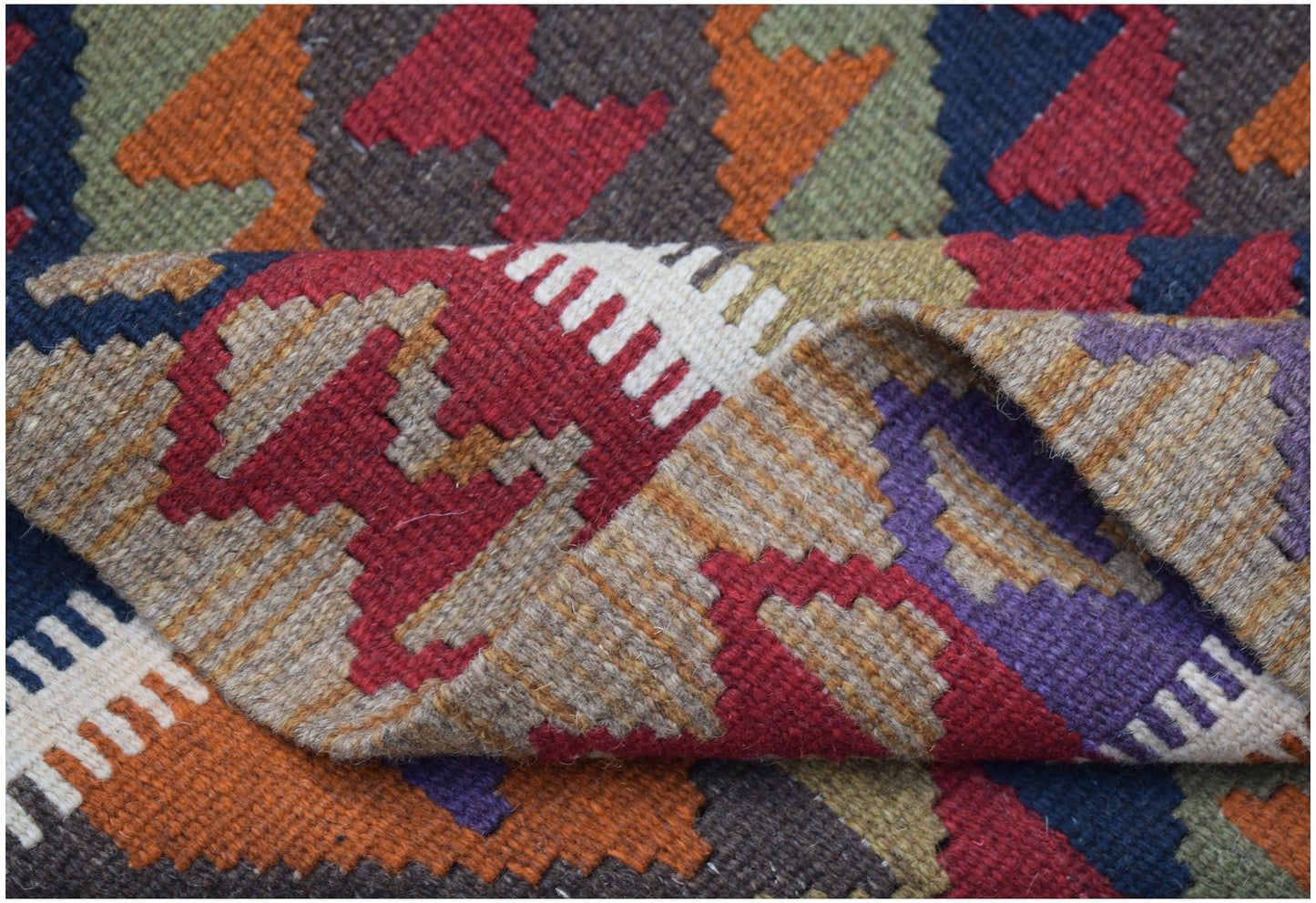 A handwoven Afghan Maimana kilim rug featuring a colorful geometric pattern in wool.
