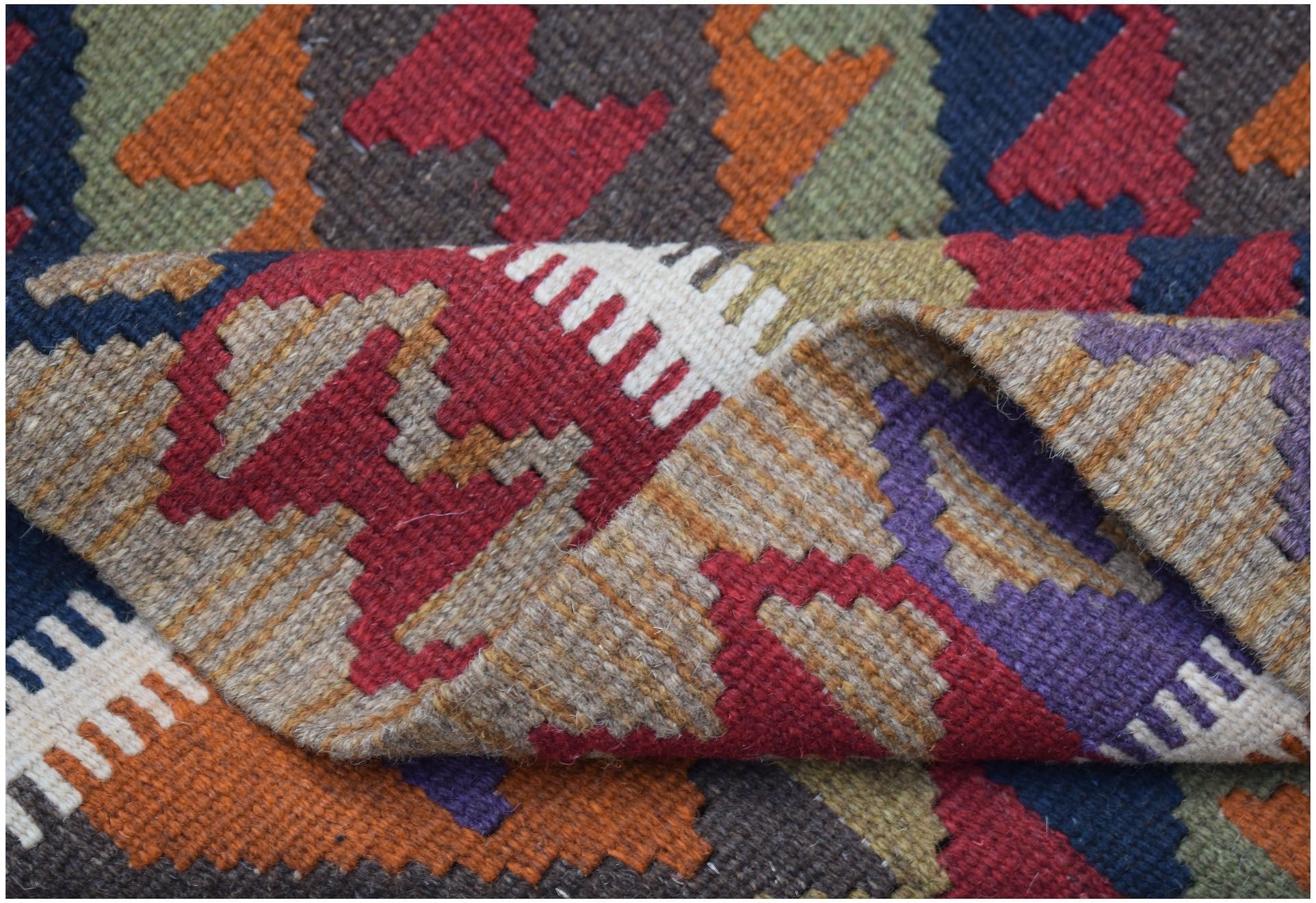 A handwoven Afghan Maimana kilim rug featuring a colorful geometric pattern in wool.