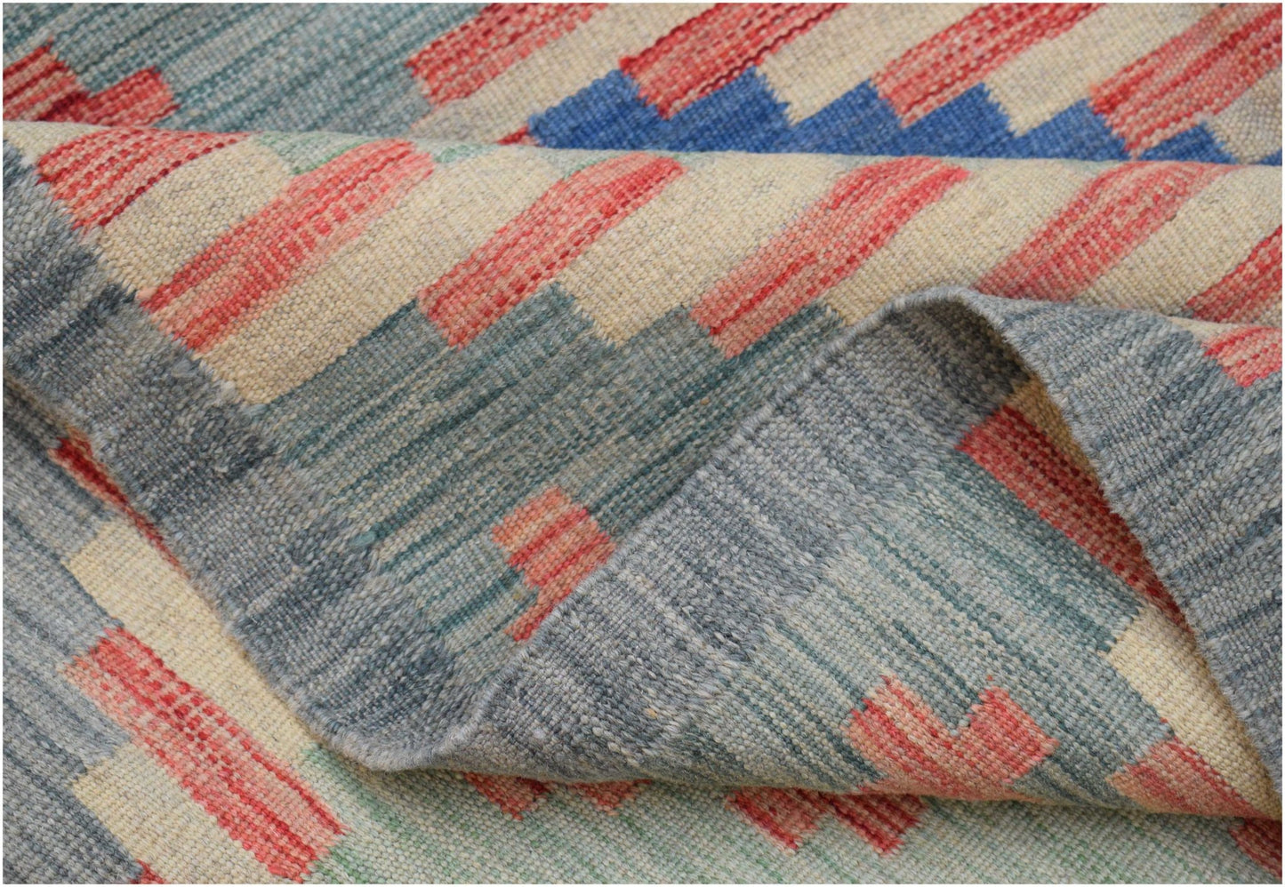 A handwoven Afghan Maimana kilim rug featuring a geometric pattern in blue, red, and cream wool.