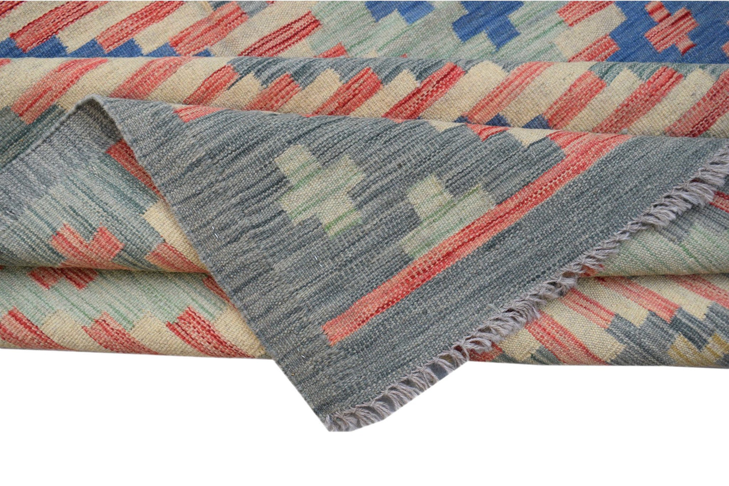 A handwoven Afghan Maimana kilim rug featuring a geometric pattern in blue, red, and cream wool.