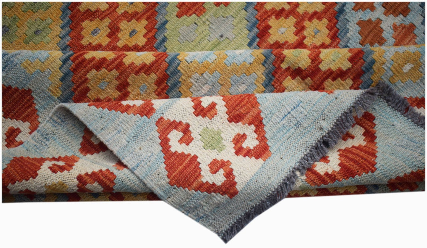 A handmade Afghan Maimana kilim rug featuring geometric patterns in red, blue, and yellow wool.