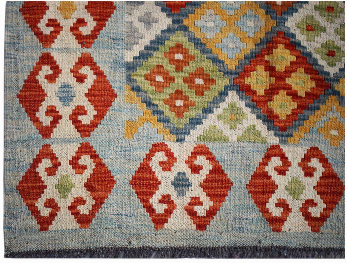 Handwoven Afghan Maimana kilim rug featuring geometric patterns in red, blue, yellow, and green.