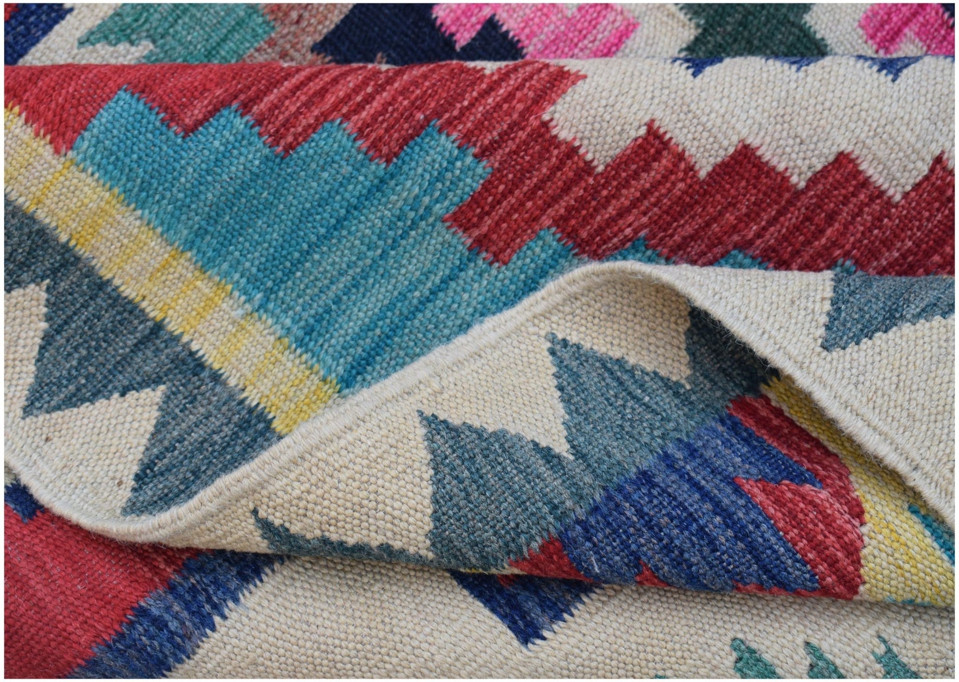 A handwoven Afghan Maimana kilim rug featuring a colorful geometric pattern on a cream background.
