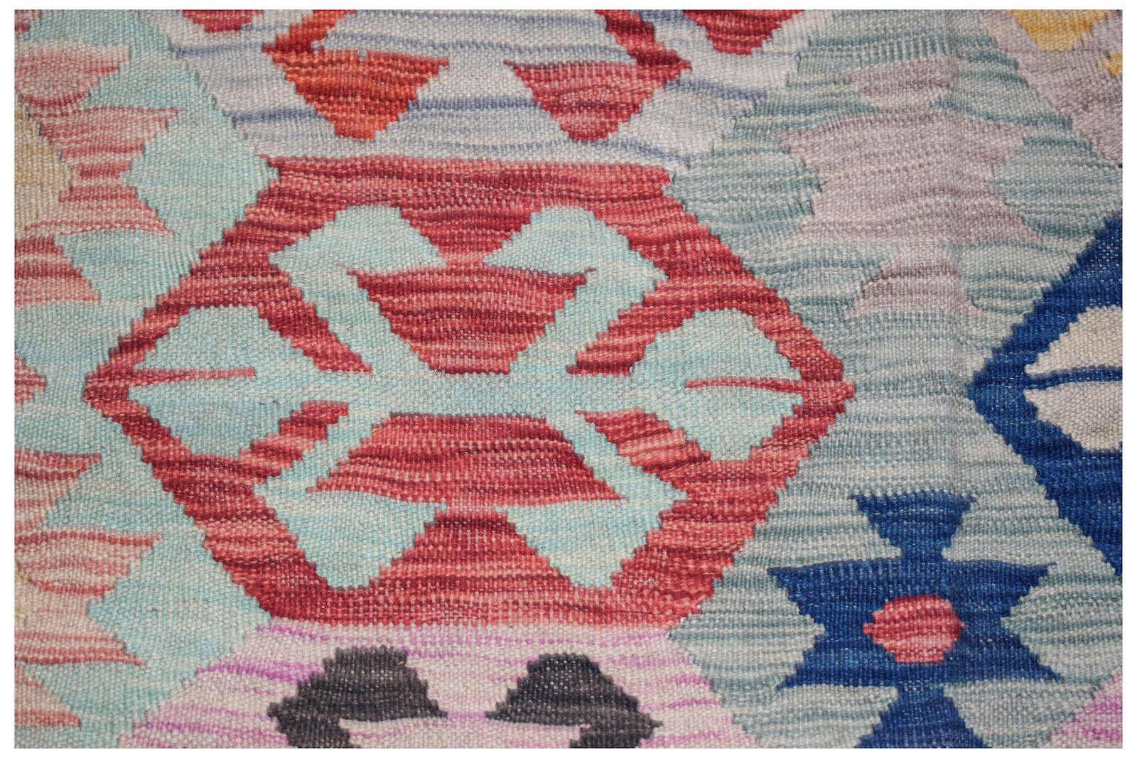 Handwoven Afghan Maimana kilim featuring a geometric pattern in vibrant red, blue, and light tones.