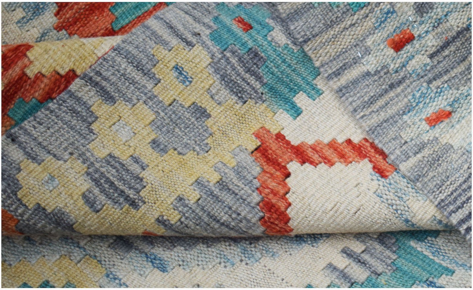 A handwoven Afghan Maimana kilim rug featuring a geometric pattern in red, blue, and yellow.