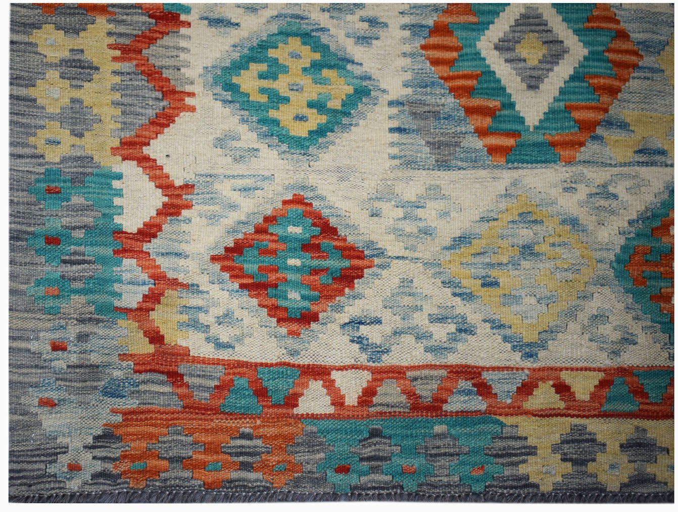 Handwoven Afghan Maimana kilim featuring a geometric pattern in vibrant red, blue, and yellow.