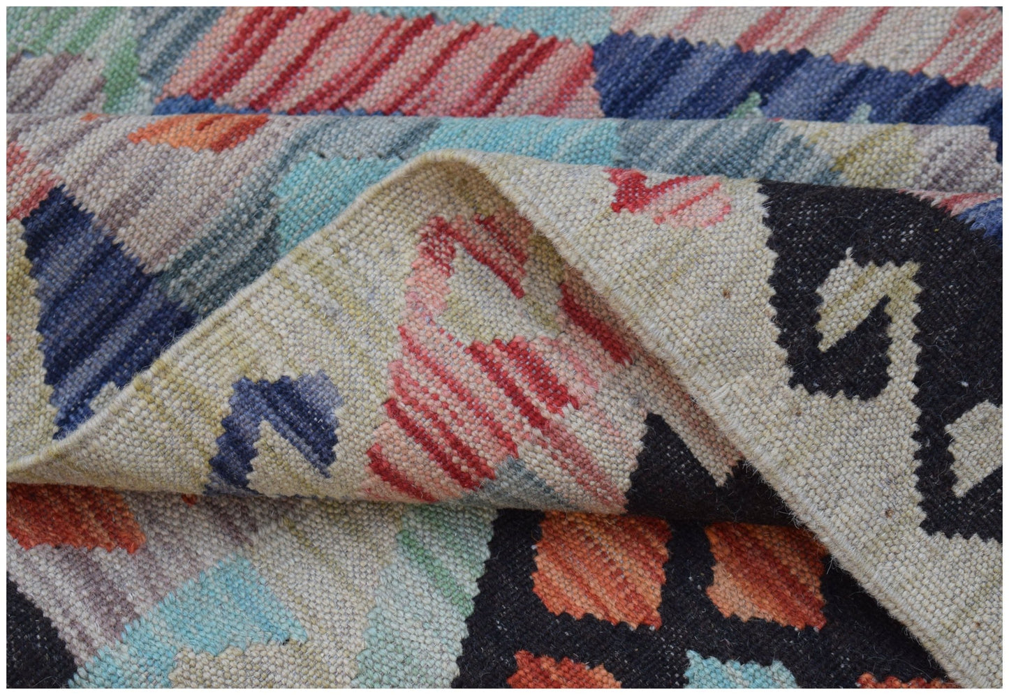 A handwoven Afghan Maimana kilim rug featuring a colorful geometric pattern and flatweave texture.