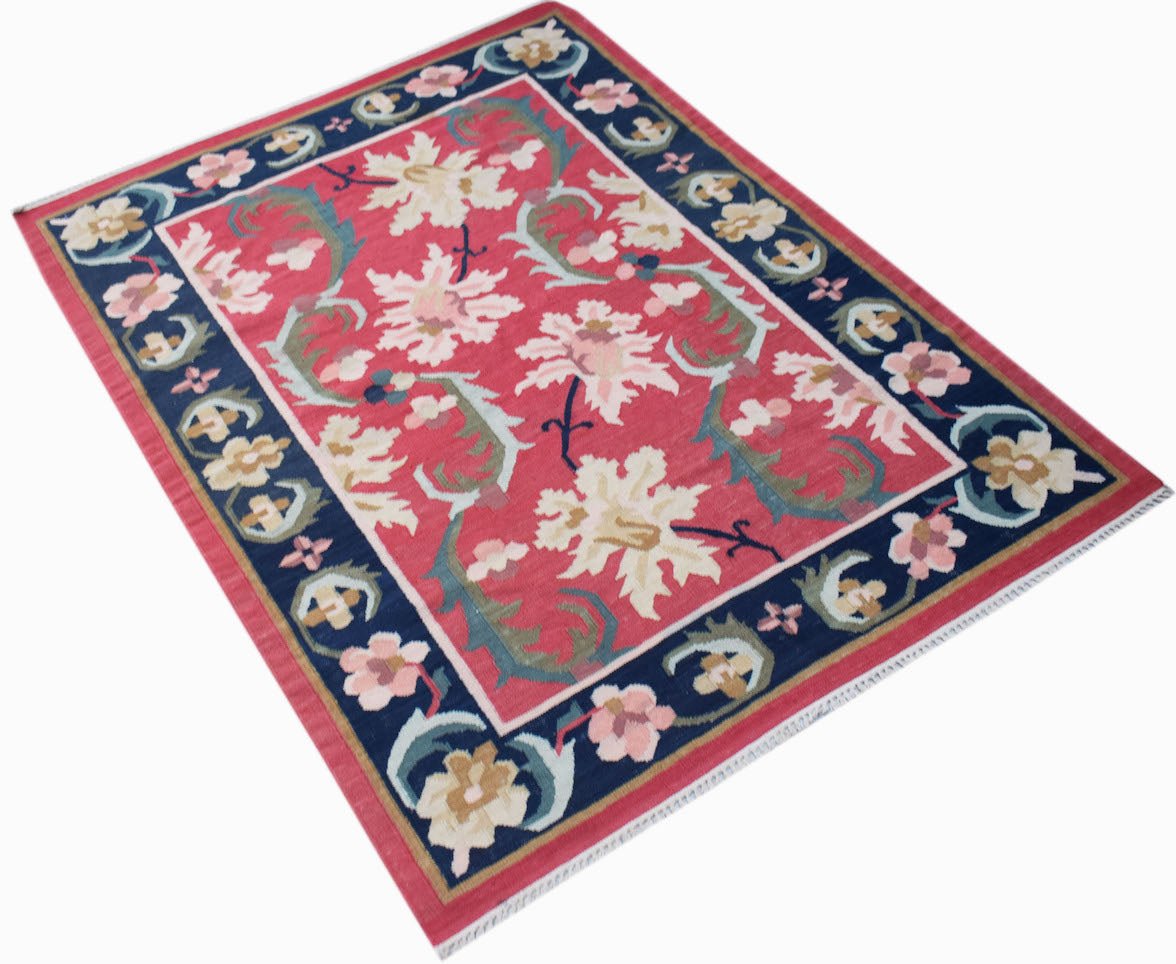 A rectangular Afghan Maimana kilim featuring a floral pattern in cream and pink on a red field.