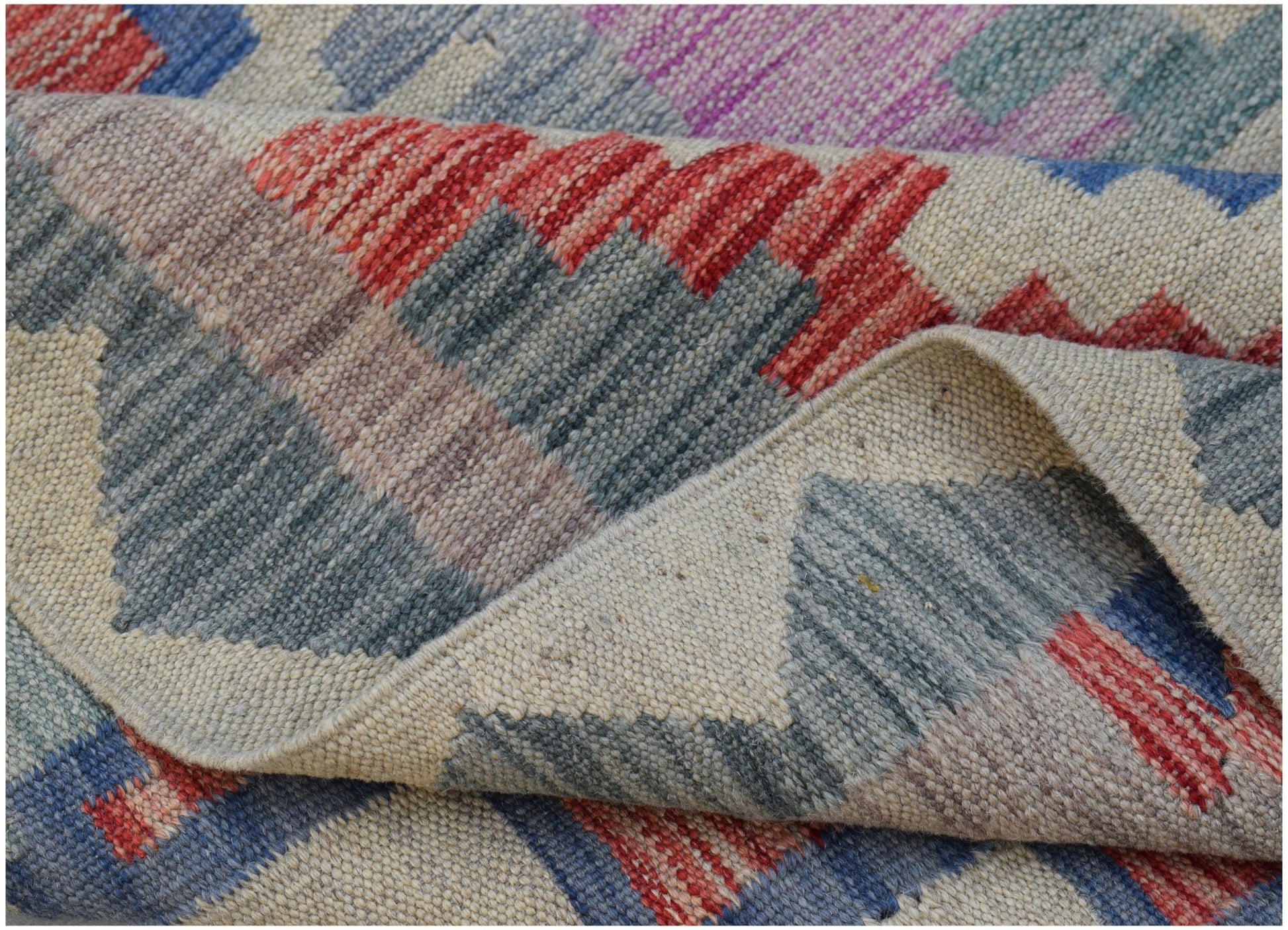 A handwoven Afghan Maimana kilim rug featuring a geometric pattern in red, blue, and grey tones.