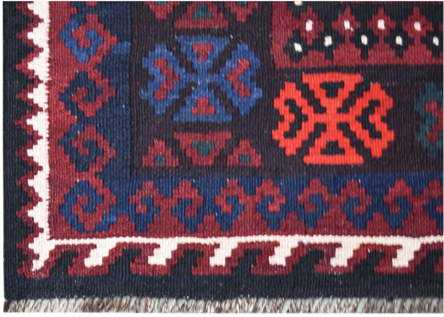 Handwoven Afghan Maimana kilim featuring geometric patterns in red, blue, and black wool.