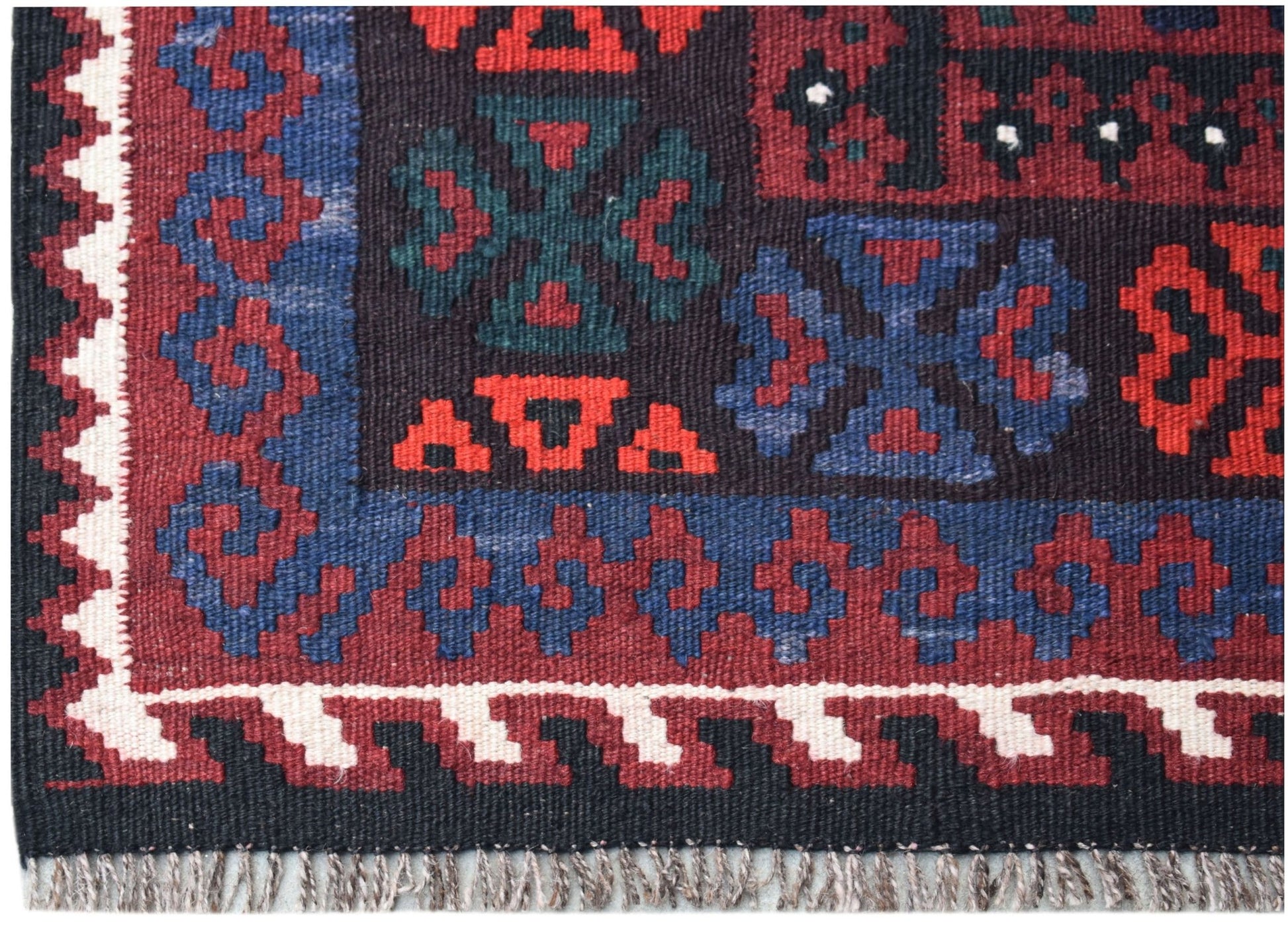 A handmade Afghan Maimana kilim featuring geometric patterns in red, blue, and black wool.
