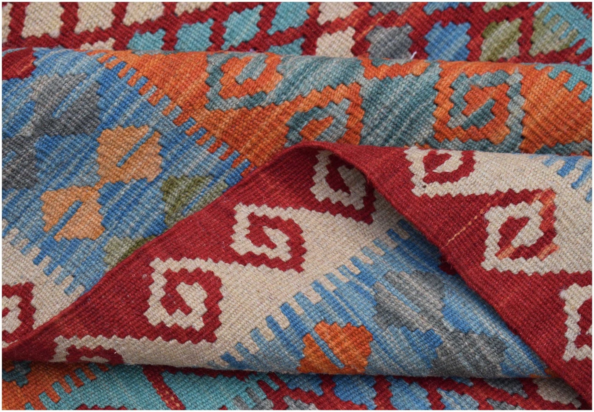 A handwoven Afghan Maimana kilim rug featuring a geometric pattern in red, blue, and orange wool.