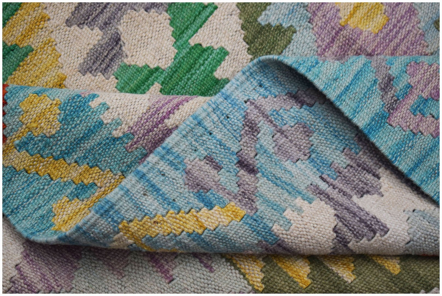 A handmade Afghan Maimana kilim rug featuring a colorful geometric pattern in wool.