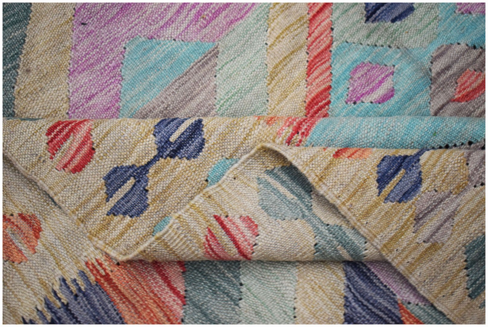 A handwoven Afghan Maimana kilim rug featuring a colorful geometric pattern on a flat wool weave.