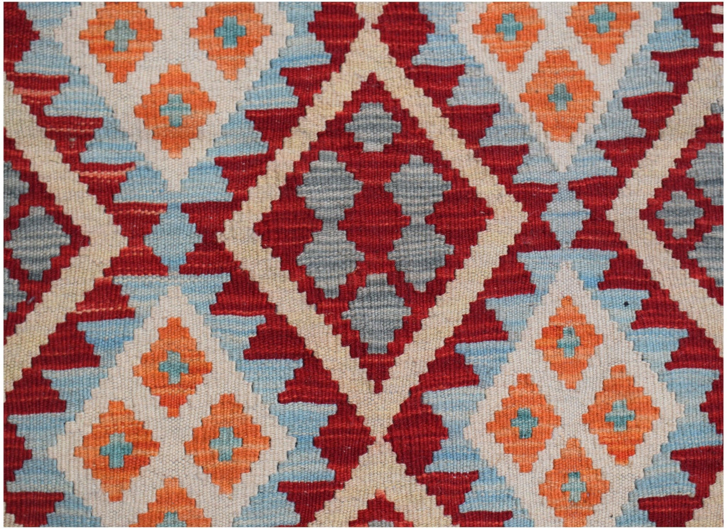 Handwoven Afghan Maimana kilim featuring a geometric diamond pattern in red, orange, and blue.