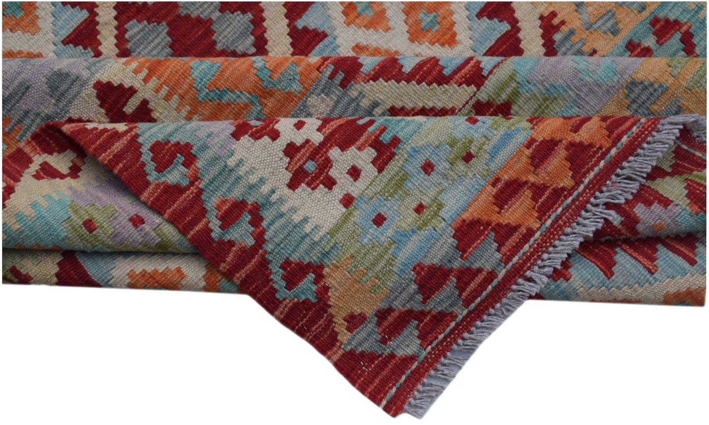 A handwoven Afghan Maimana kilim rug featuring a colorful geometric pattern and fringed edges.