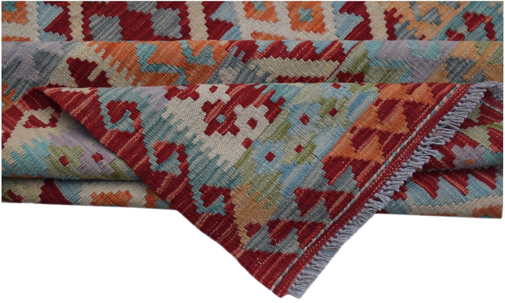 A handwoven Afghan Maimana kilim rug featuring a colorful geometric pattern and fringed edges.