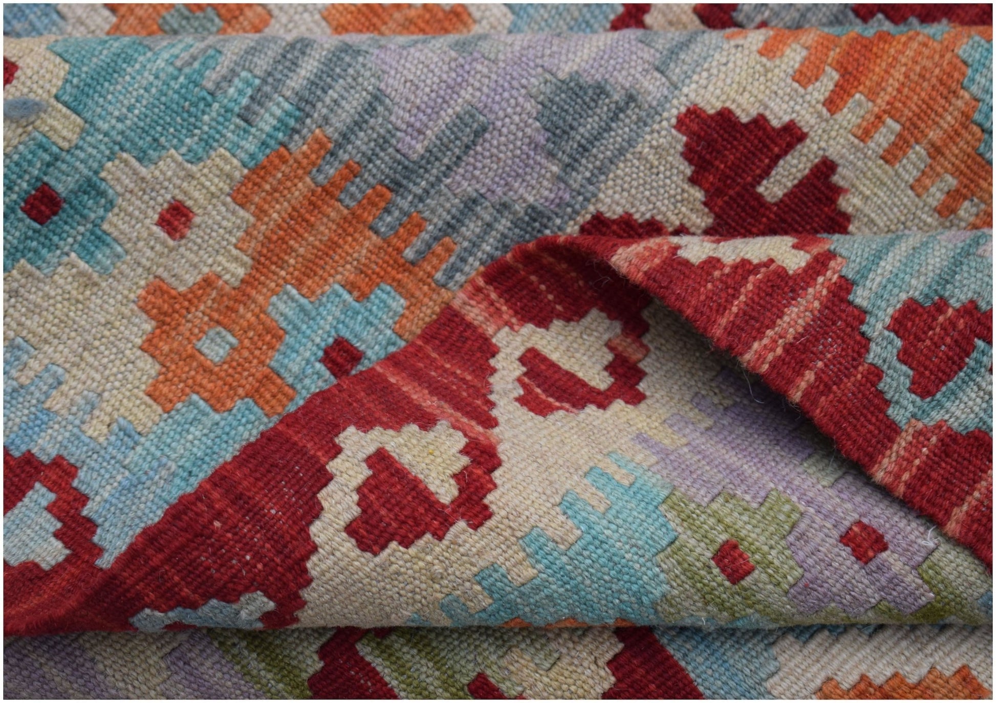 A handwoven Afghan Maimana kilim rug featuring a vibrant geometric pattern in wool.