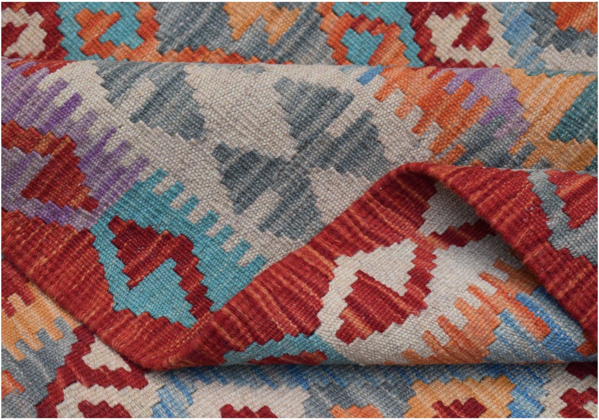 A handwoven Afghan Maimana kilim rug featuring a vibrant geometric pattern in wool.