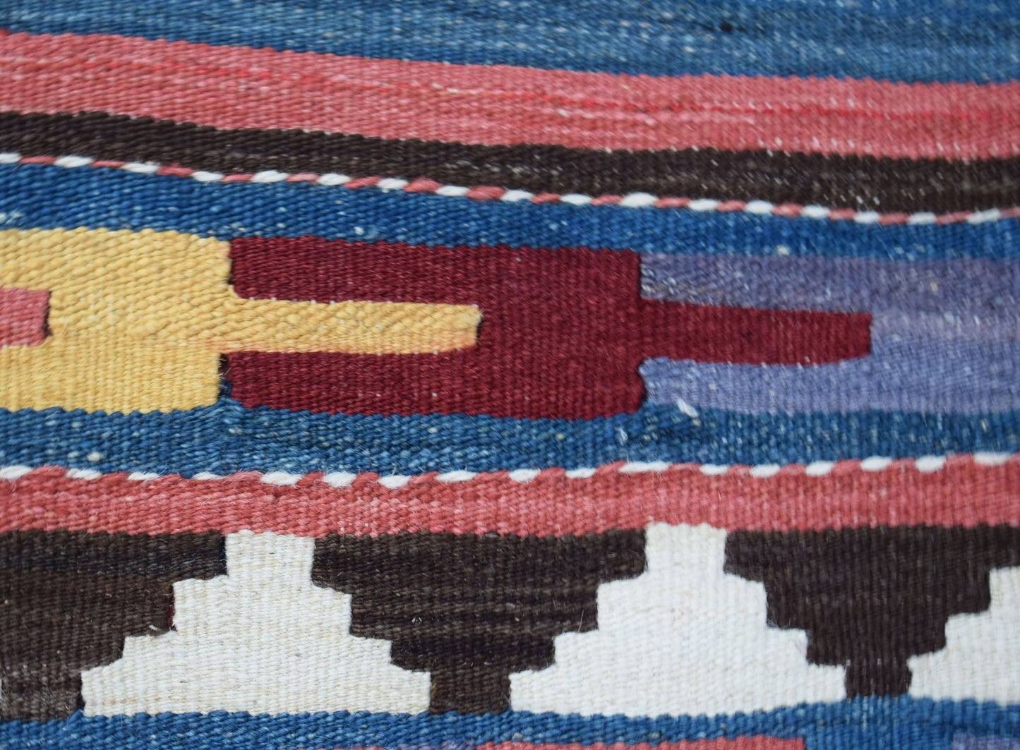 A close-up of a handwoven Afghan Maimana kilim featuring geometric patterns in wool.