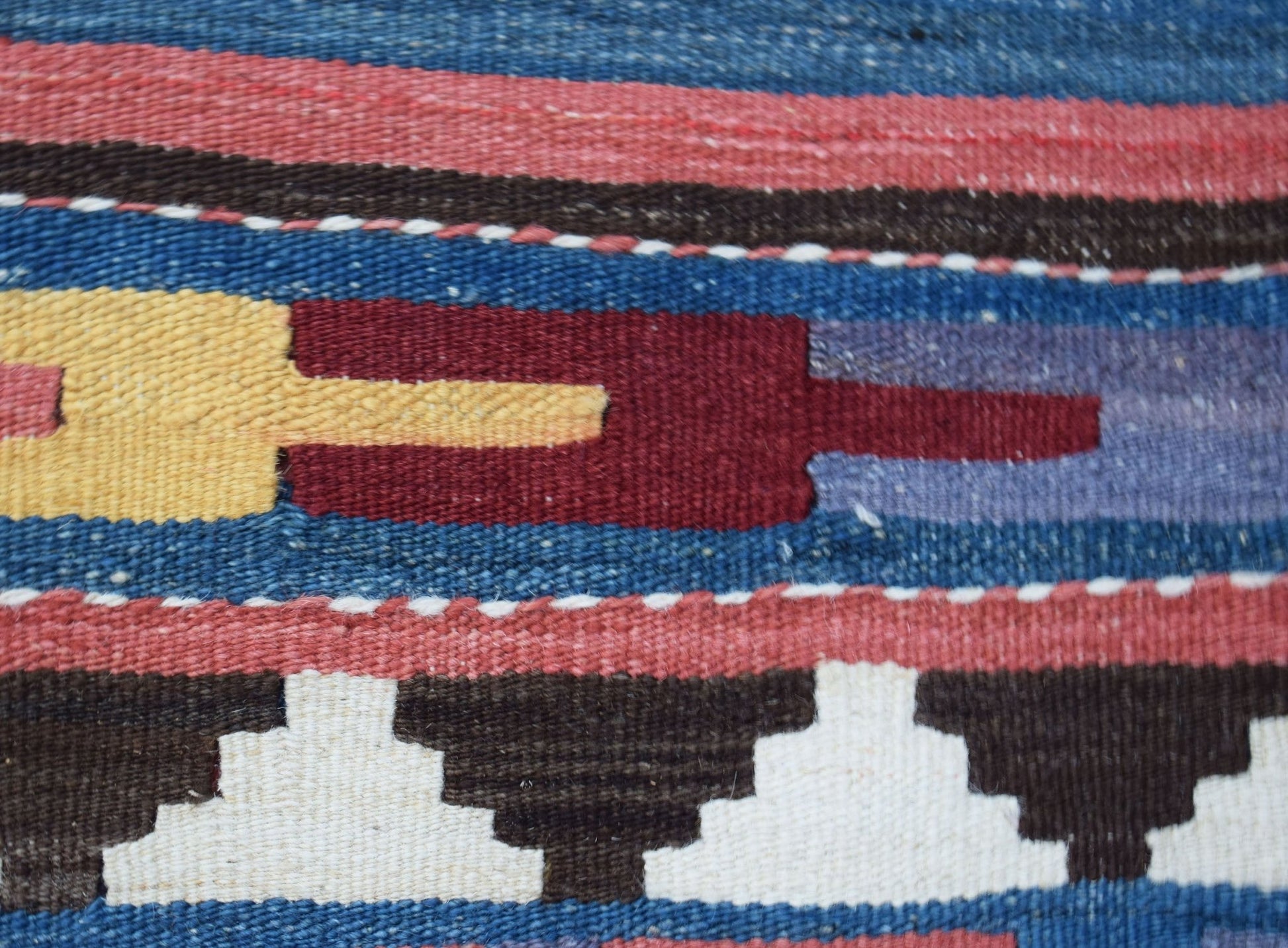 A close-up of a handwoven Afghan Maimana kilim featuring geometric patterns in wool.