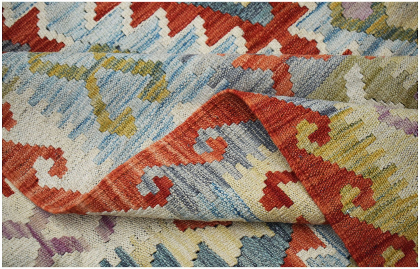A handwoven Afghan Maimana kilim rug featuring a geometric pattern in red, blue, and yellow.