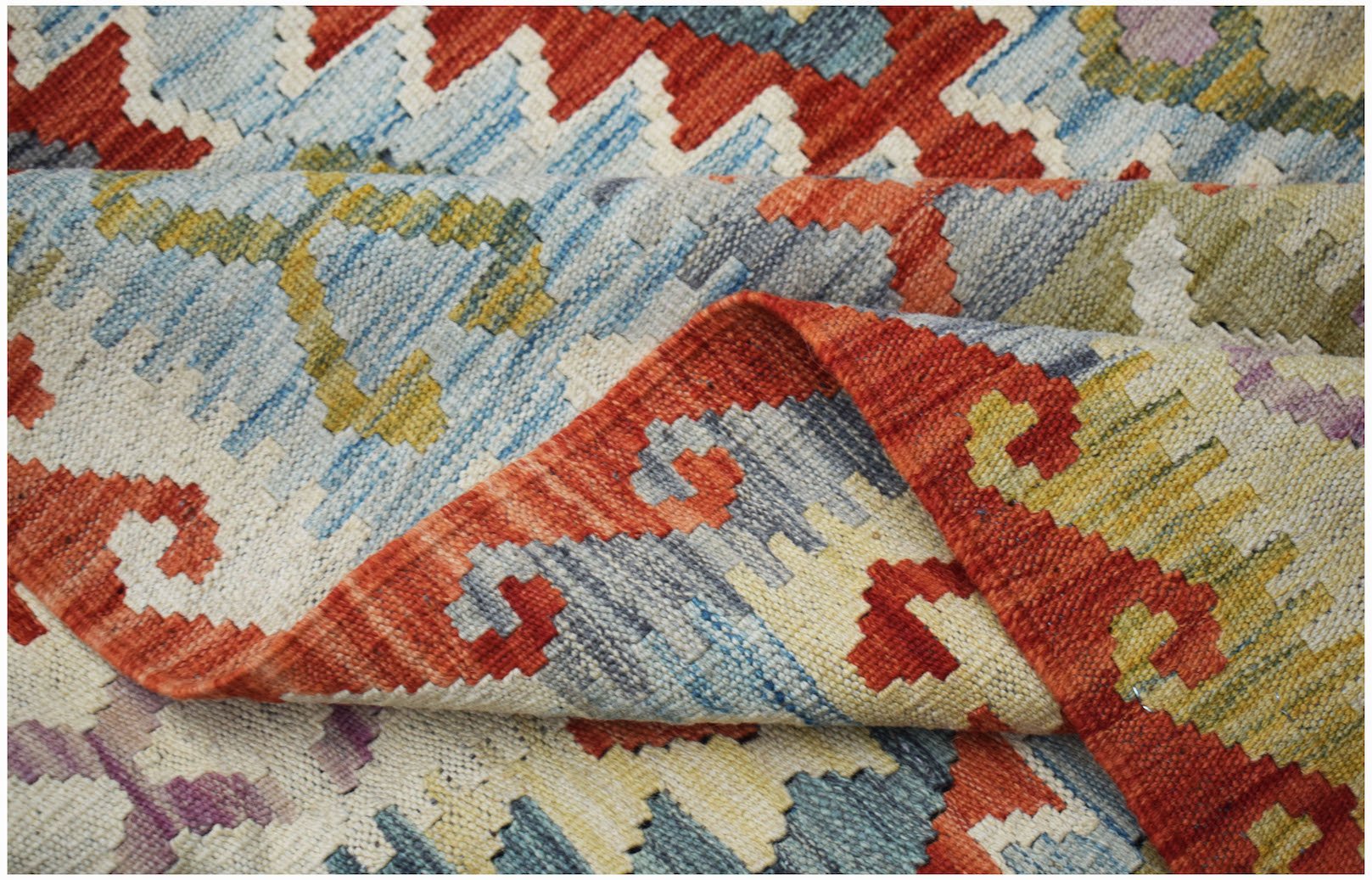 A handwoven Afghan Maimana kilim rug featuring a geometric pattern in red, blue, and yellow.