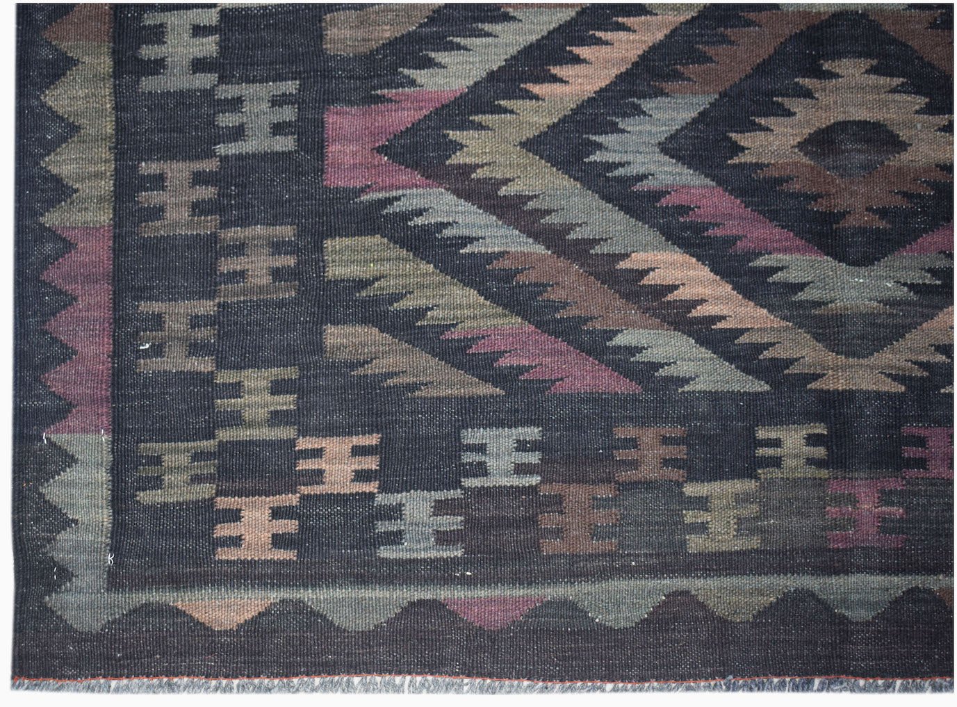 Handwoven Afghan Maimana kilim featuring a dark background with geometric patterns in muted tones.