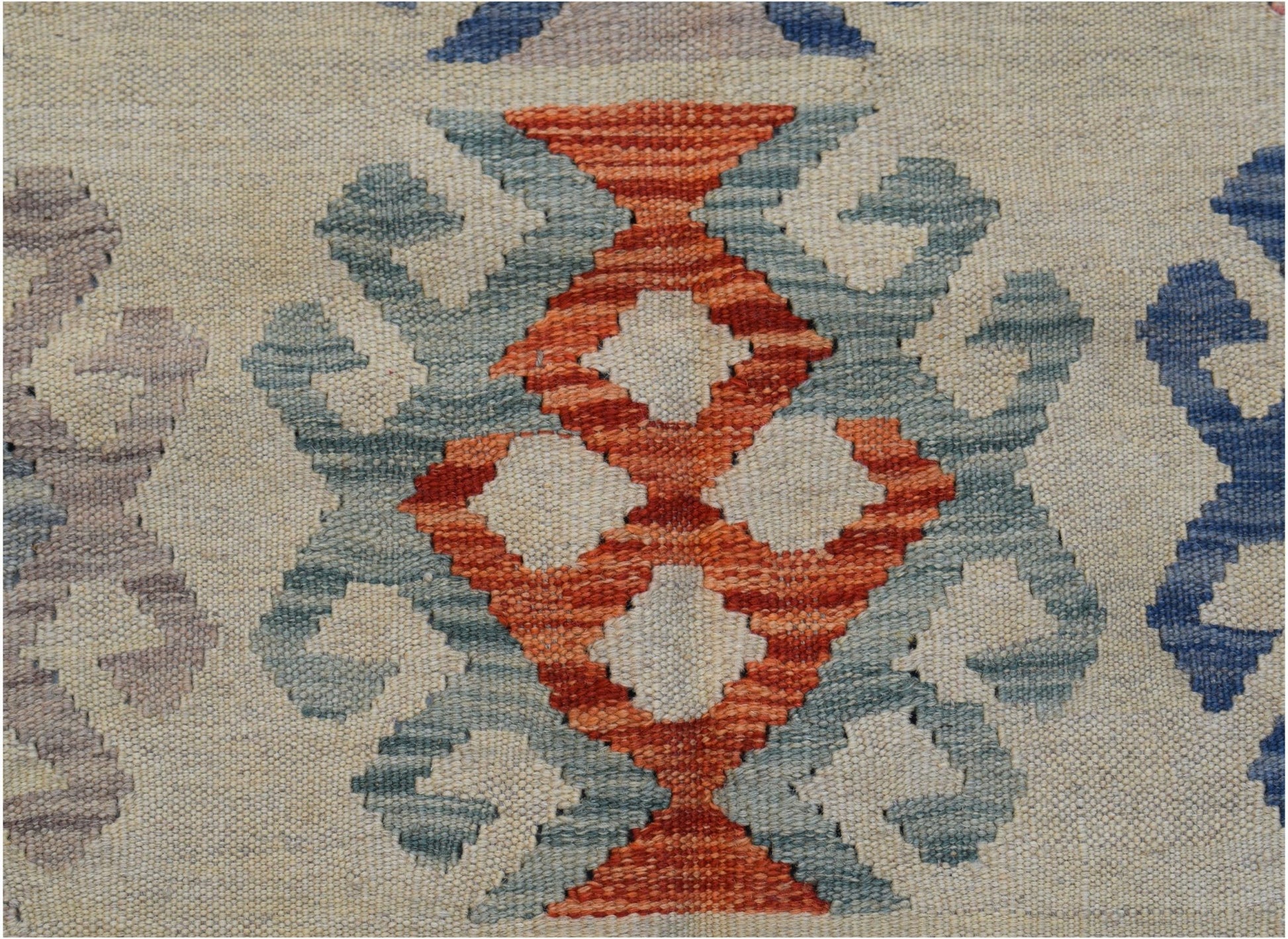 A close-up of an Afghan Maimana kilim featuring a geometric orange and blue pattern on a cream base.