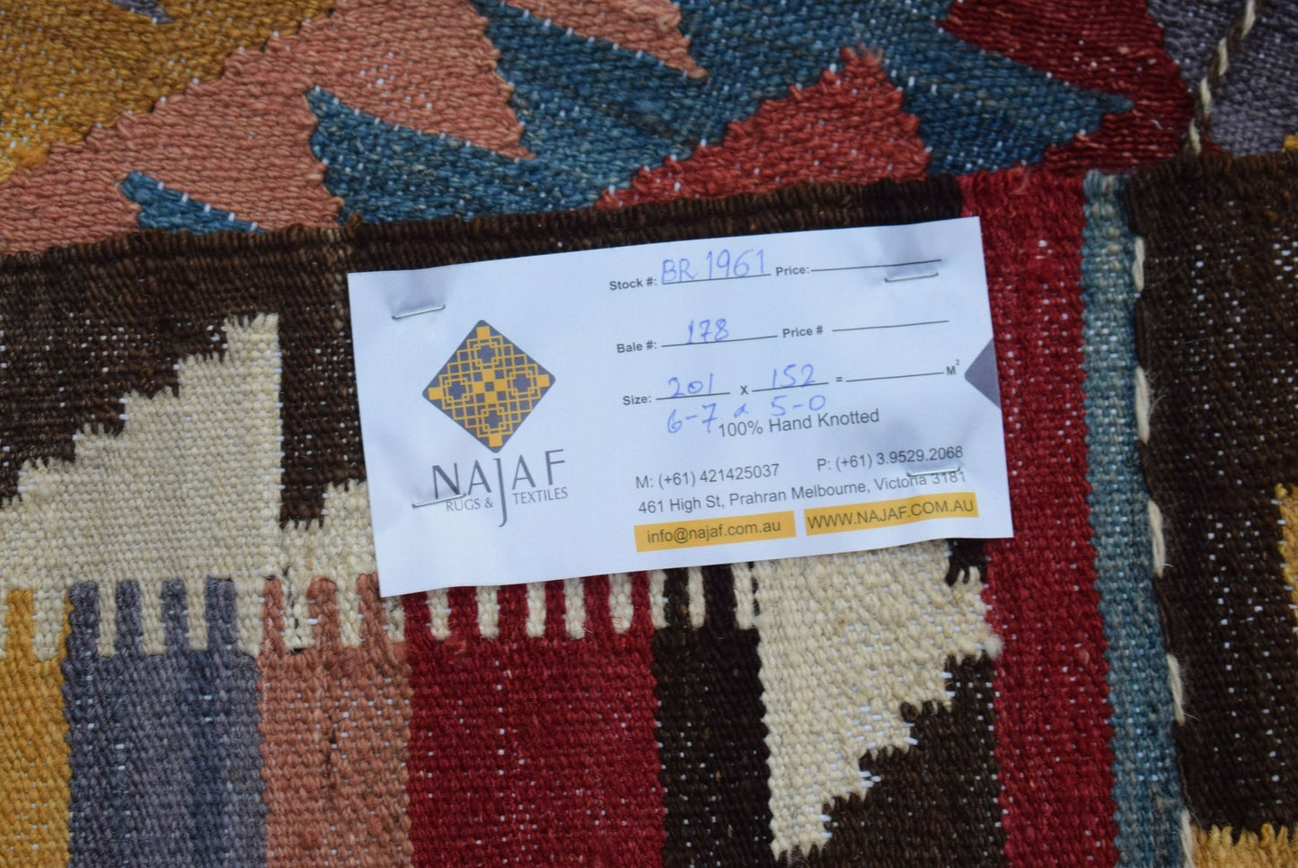 A close-up of a handwoven Afghan Maimana kilim featuring a colorful geometric pattern.