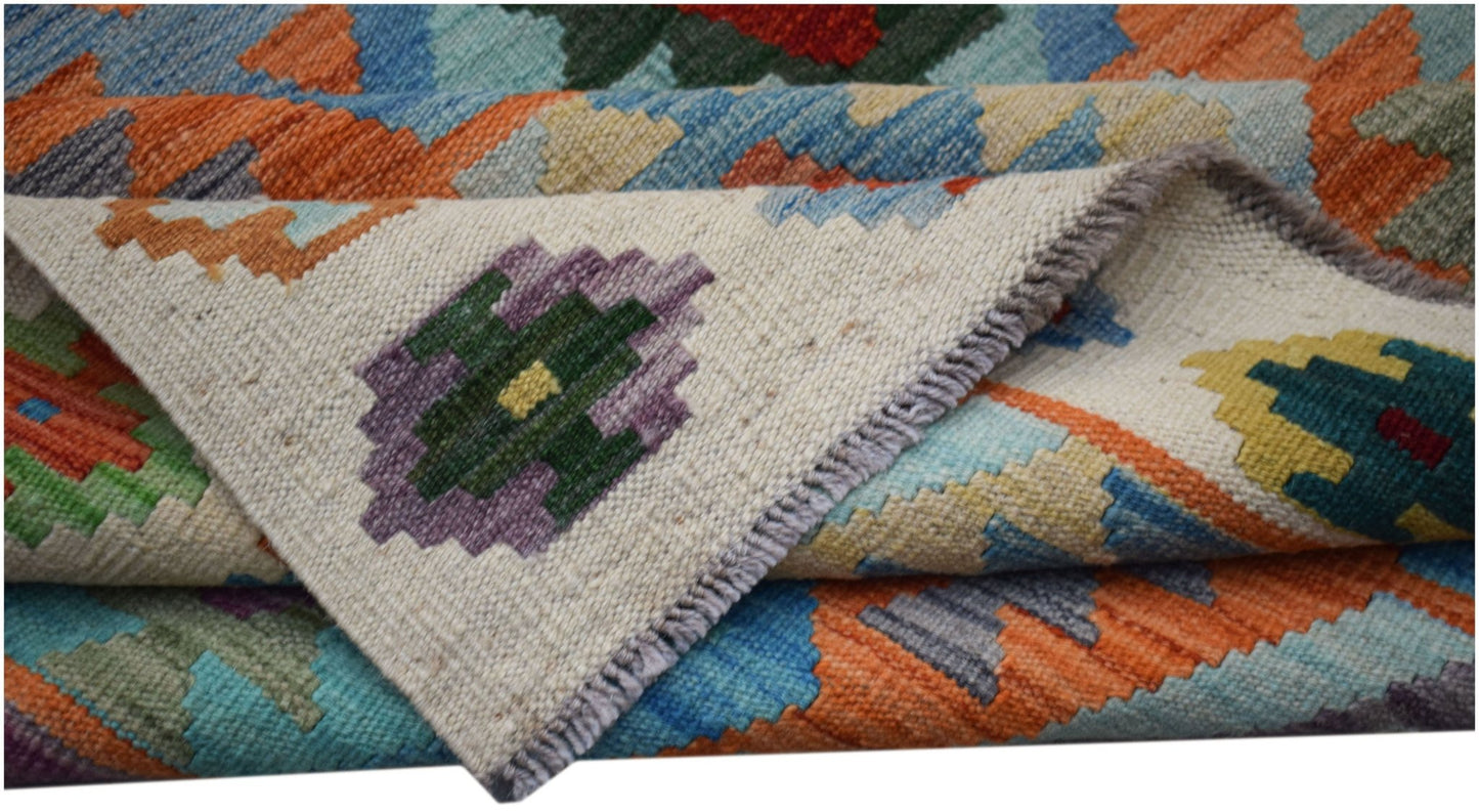 A handwoven Afghan Maimana kilim rug featuring a colorful geometric pattern on a cream background.