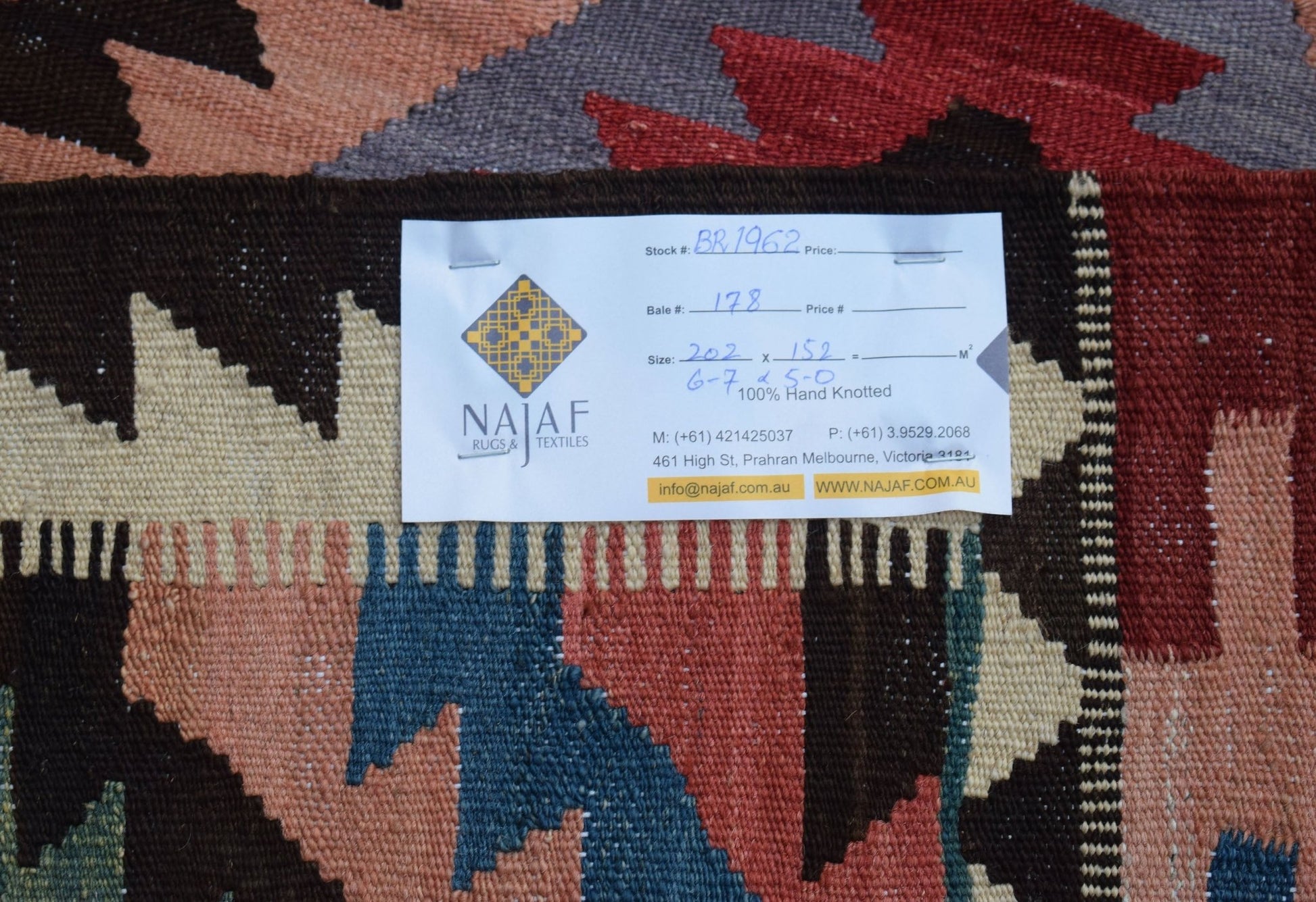 A handwoven Afghan Maimana kilim featuring a geometric pattern in shades of red, blue, and cream.