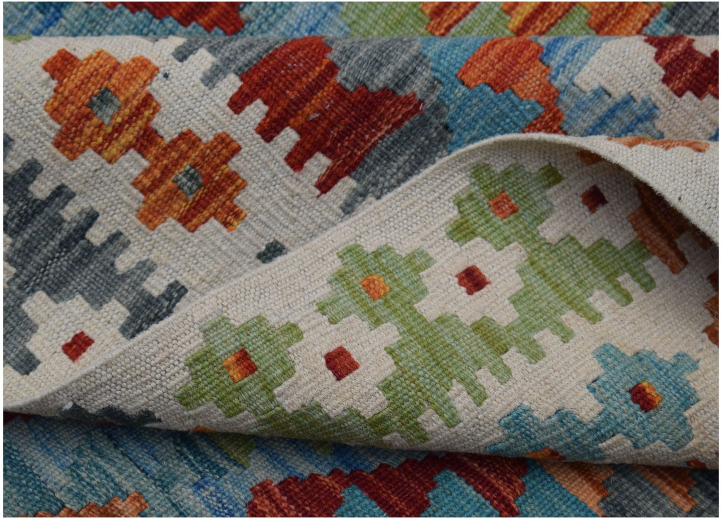 A handwoven Afghan Maimana kilim rug featuring a colorful geometric pattern on a cream background.