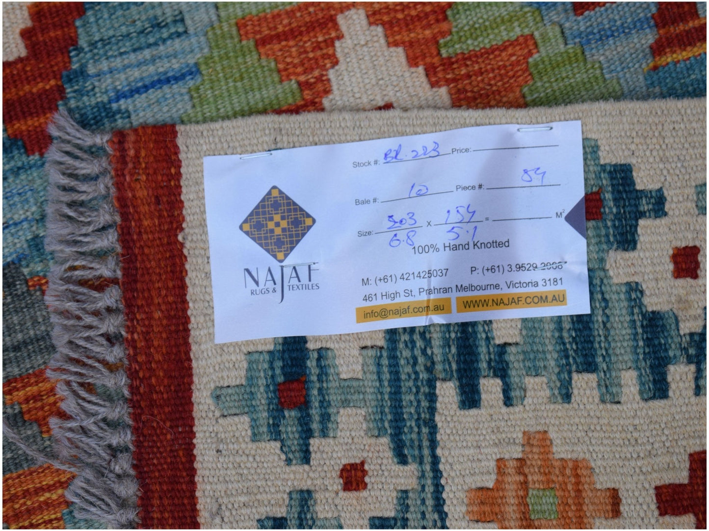 A handwoven Afghan Maimana kilim featuring a geometric pattern in vibrant orange, blue, and cream.