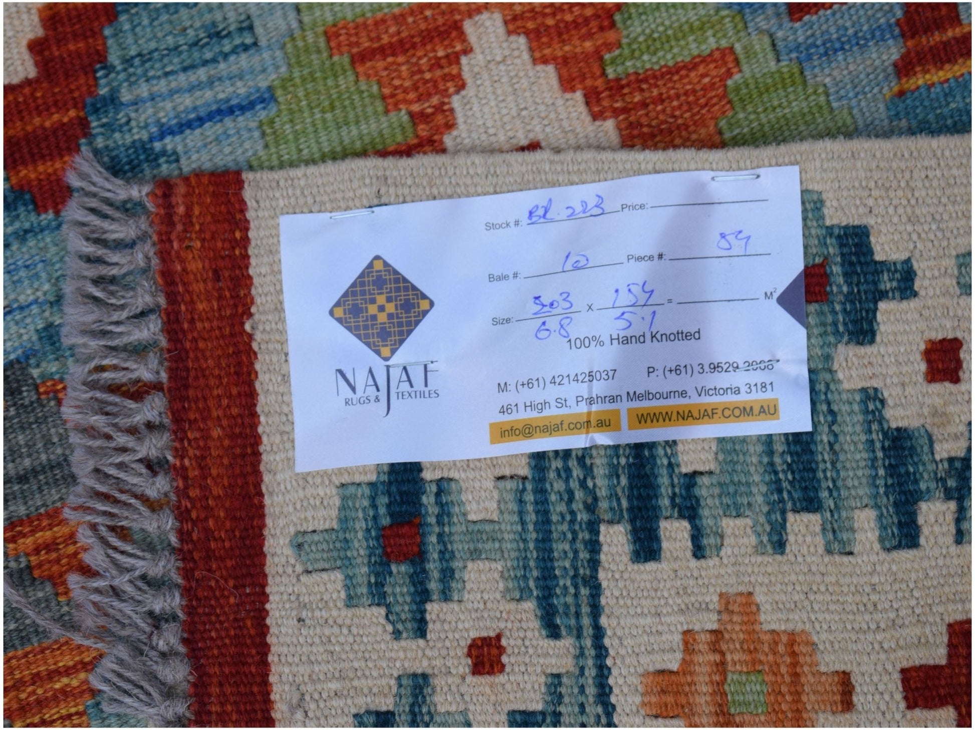 A handwoven Afghan Maimana kilim featuring a geometric pattern in vibrant orange, blue, and cream.