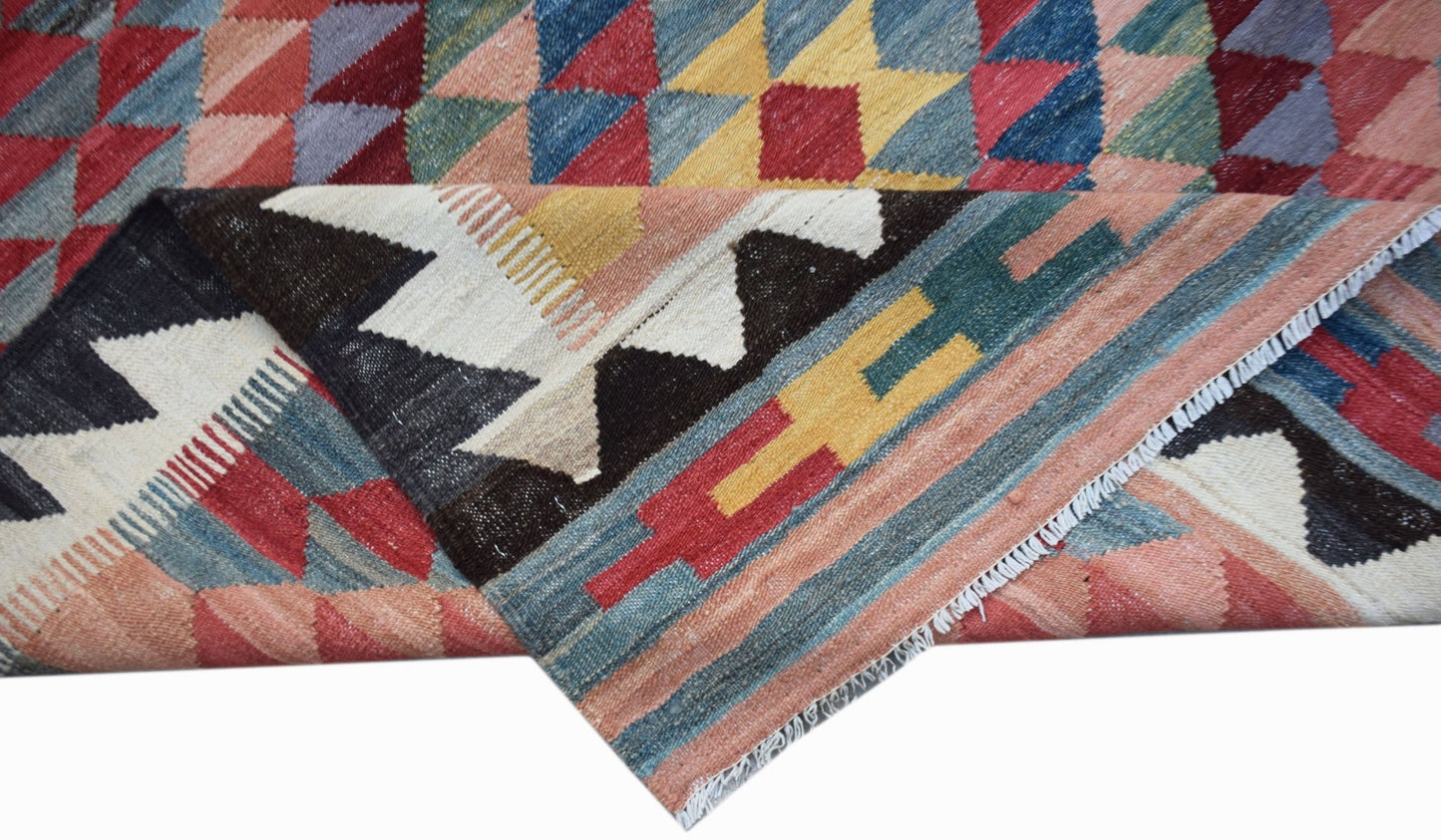 A handmade Afghan Maimana kilim rug featuring a geometric pattern in vibrant multicolored wool.